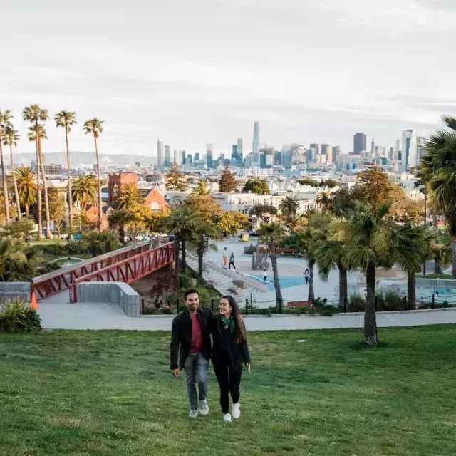 Dolores Parkとサンフランシスコのスカイラインを背に、カップルがカメラに向かって歩いています。